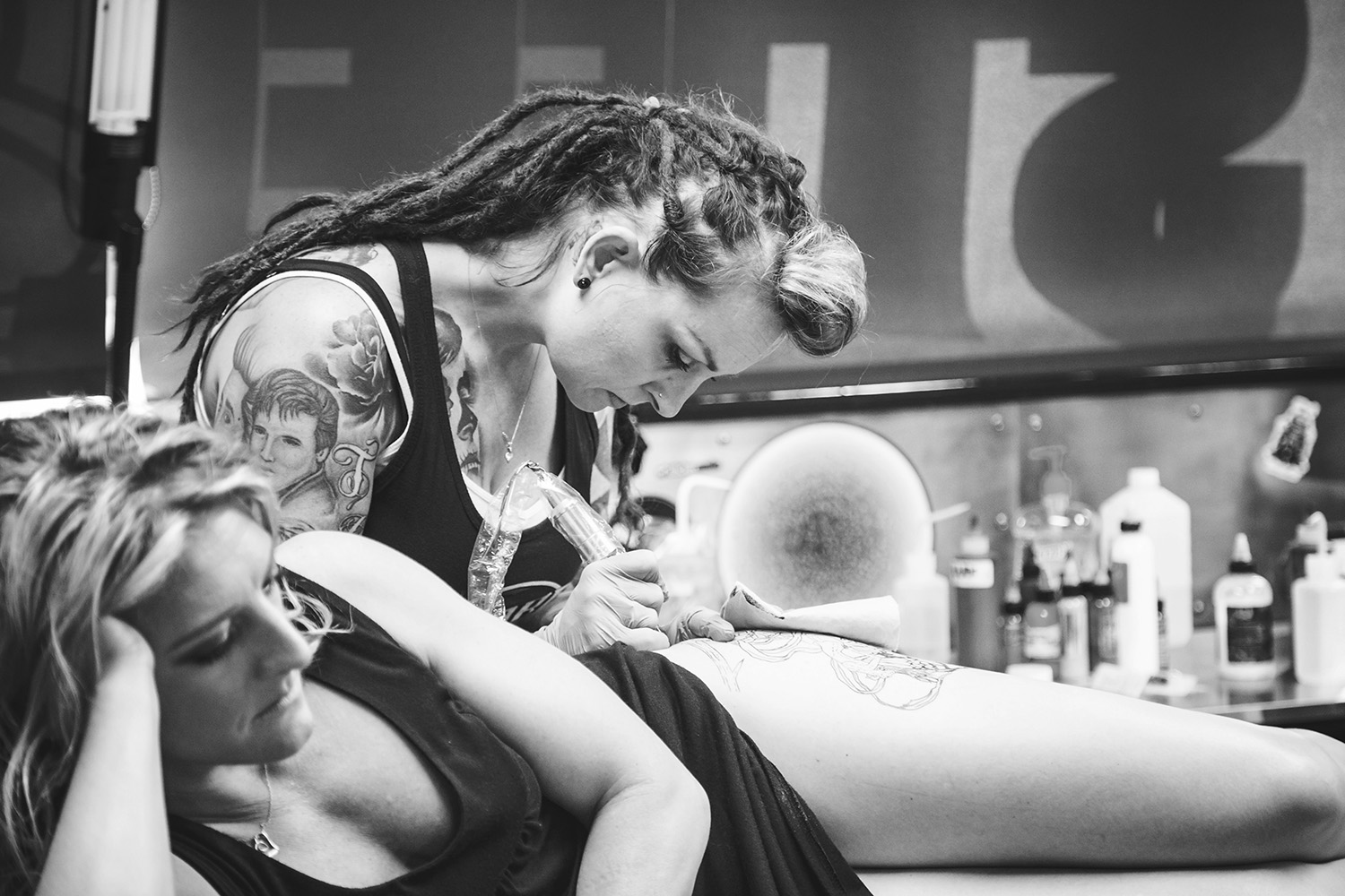 An artist tattooing a woman’s backside