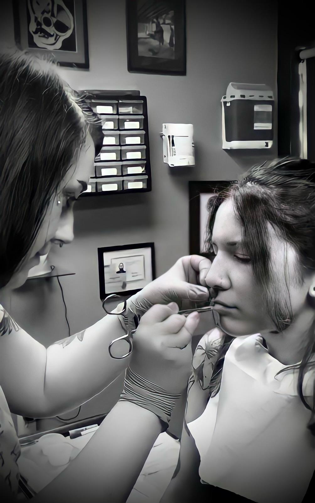 Tattoo artist holding a pair of forceps near a woman’s face