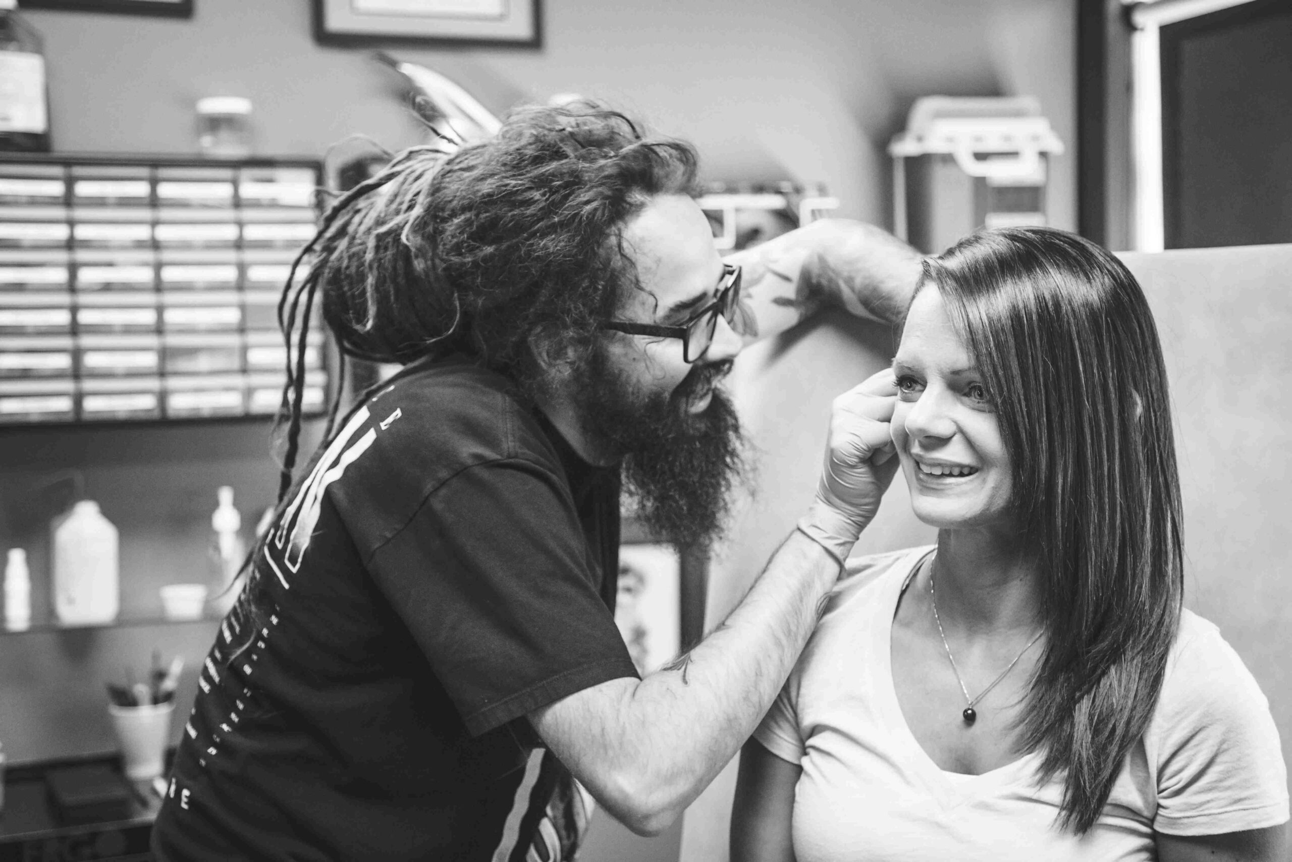 A man is getting a tattoo on a woman's head.